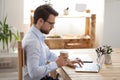 Focused male employee working at laptop drinking coffee