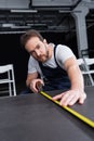 Focused male craftsman in working overall making measurements of floor by