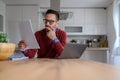 Focused male entrepreneur analyzing business report and working over laptop on desk in home office Royalty Free Stock Photo