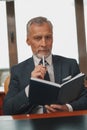 Focused Male hotelier making notes in diary while sitting in his office in hotel Royalty Free Stock Photo