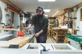 Focused male manual worker using table saw in protective gear. Professional male carpenter during work on a project. Royalty Free Stock Photo