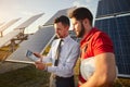 Focused male supervisor sharing tablet with technician near solar panels Royalty Free Stock Photo