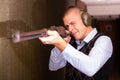 Focused man aiming shotgun at target in shooting range