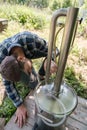 Focused man makes an alcohol mashine in a village courtyard, on a summer day. Preparation of an alcoholic beverage.