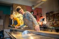 Man carpenter measures wood for sawing with tape measure in carpentry workshop with woman colleague Royalty Free Stock Photo