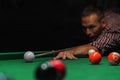 A focused man is lining up a shot in a game of billiards on a green felt table Royalty Free Stock Photo