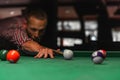 A focused man is lining up a shot in a game of billiards on a green felt table Royalty Free Stock Photo