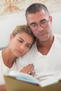 Focused man and woman lying in bed and reading book in morning Royalty Free Stock Photo