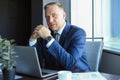 Focused mature businessman deep in thought while sitting at a table in modern office