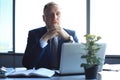 Focused mature businessman deep in thought while sitting at a table in modern office