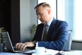 Focused mature businessman deep in thought while sitting at a table in modern office