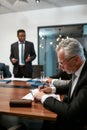 Focused mature caucasian businessman writing something in his note pad while having a meeting in the modern office Royalty Free Stock Photo