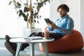 Focused mature entrepreneur using digital tablet at workplace, sitting in bean bag chair at office, copy space Royalty Free Stock Photo