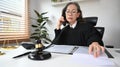 Focused mature female judge or lawyer in robe gown uniform working with contract papers in the office Royalty Free Stock Photo