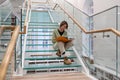 Curious female reader sits on modern glass stairs step reading favorite book about world history
