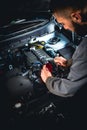Focused mechanic doing car repair. Disconnecting the battery terminal of modern car.