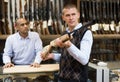 Man examining break-barrel air shotgun in gunsmith store Royalty Free Stock Photo