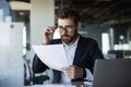 Focused middle aged businessman working with papers in modern office interior, reading financial documents Royalty Free Stock Photo