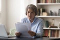 Focused middle aged businesswoman doing financial paperwork.