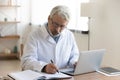 Focused middle aged male doctor working at clinic office.