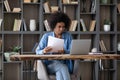 Focused millennial Afro American entrepreneur girl doing paperwork at laptop Royalty Free Stock Photo