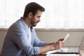 Focused millennial man read letter at home