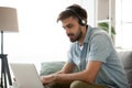 Focused millennial man in headset using computer online