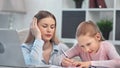 Focused mother and smiling pupil teen daughter doing school homework together medium close-up