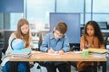 Focused multiracial students kids writing down data into notebook while sitting at table