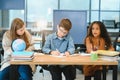 Focused multiracial students kids writing down data into notebook while sitting at table