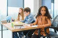 Focused multiracial students kids writing down data into notebook while sitting at table