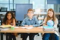 Focused multiracial students kids writing down data into notebook while sitting at table