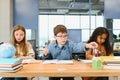 Focused multiracial students kids writing down data into notebook while sitting at table