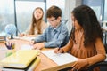 Focused multiracial students kids writing down data into notebook while sitting at table