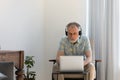 Focused older man in wireless headset using laptop at home Royalty Free Stock Photo