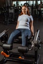 Overweight girl doing leg extension exercise on training machine