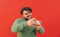 Focused overweight hispanic guy is enjoying playing games on his smartphone, being concentrated on the process, smiling and