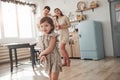 Focused photo. Playful female child have fun by running in the kitchen at daytime of front of her mother and father