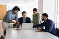 Focused polyethnic businesspeople engaged in brainstorm looking at notebook screen Royalty Free Stock Photo