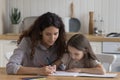 Focused positive mom and girl kid drawing in colorful pencils