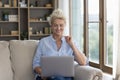 Focused positive senior freelance woman holding laptop computer on lap