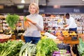 Focused middle aged woman shopping in organic food store, choosing fresh vegetables Royalty Free Stock Photo