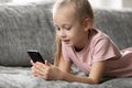 Focused preschooler child girl resting on sofa at home