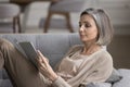 Focused pretty grey haired woman reading bestseller paper book