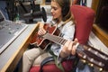 Focused pretty singer recording and playing guitar