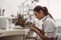 Focused on a process. Portrait of young female jeweler focused on creating a silver ring at her modern workbench.