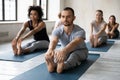 Focused professional male instructor leading yoga class in modern studio.