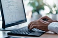 A focused programmer is diligently working on writing code while using a modern computer set up in a bright and airy