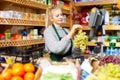 Focused saleswoman weighing grape on scale in grocery store Royalty Free Stock Photo