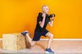 Focused senior fit man doing weight lifting workout exercise staning at the gym  on orange background. mature people Royalty Free Stock Photo